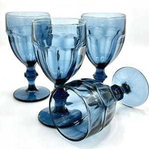 May include: Four blue glass goblets with a textured design. The goblets are stacked on top of each other.