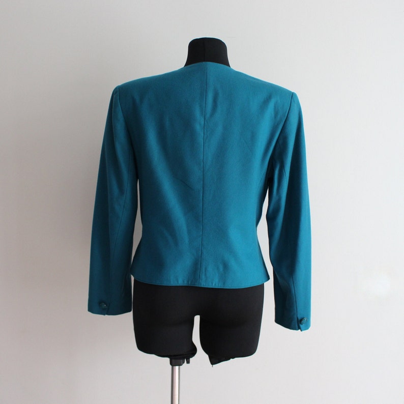 May include: A teal blazer with long sleeves and a button fastening. The blazer is tailored and has a fitted silhouette.