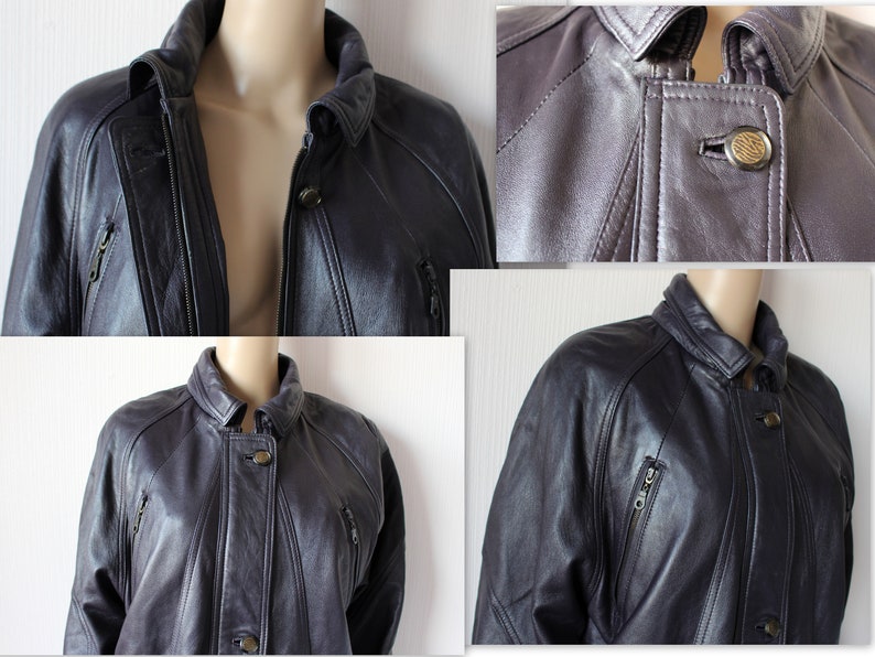 May include: A dark gray leather jacket with a zipper closure and multiple pockets. The jacket has a stand-up collar and a button closure at the neck.