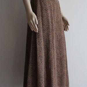May include: A brown and black leopard print midi skirt. The skirt is made of a lightweight fabric and has a flowy silhouette.