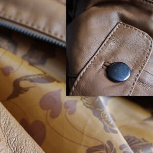 May include: Close-up of a brown leather jacket with a zipper and a button closure. The jacket has a patterned lining.