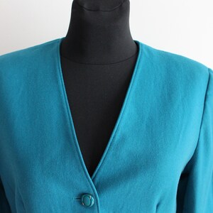 May include: A teal blue blazer with a single button fastening and a v-neck.