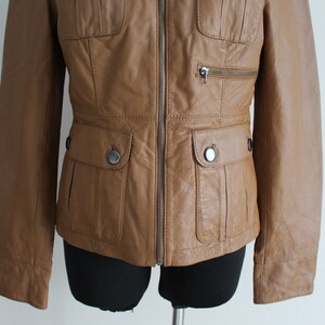 May include: A brown leather jacket with a zipper closure and two flap pockets on the front.