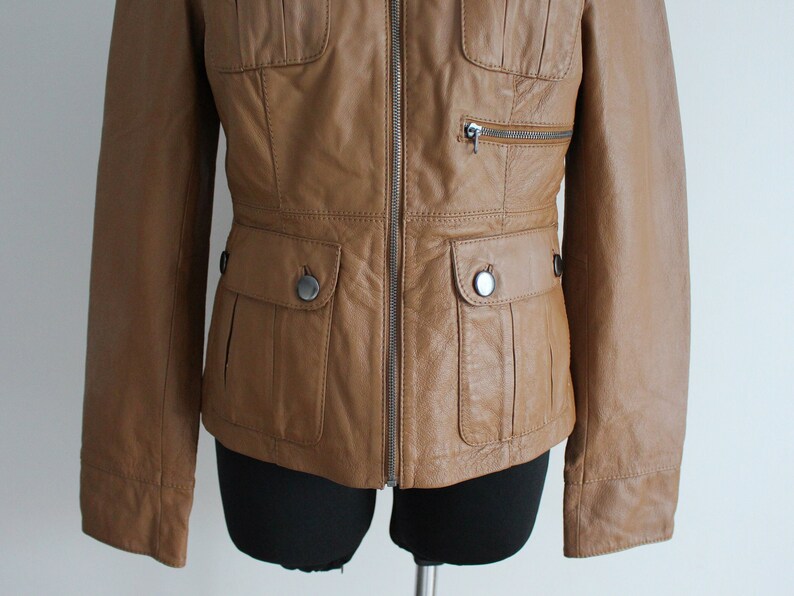 May include: A brown leather jacket with a zipper closure and two flap pockets on the front.
