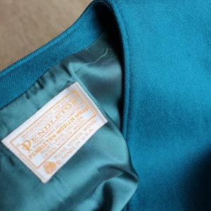 May include: A teal blue Pendleton woolen mills label with white text that reads "warranted to give satisfaction Pendleton woolen mills Portland, Oregon 100% virgin wool pure virgin wool made in U.S.A."
