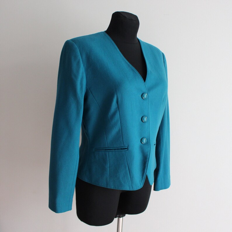 May include: Teal blazer with a v-neck and four buttons down the front.