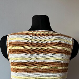 Puede incluir: Un top de crochet sin mangas con rayas marrones, blancas y amarillas.