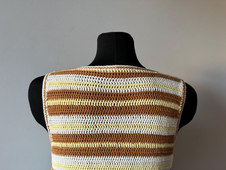 Puede incluir: Un top de crochet sin mangas con rayas marrones, blancas y amarillas.