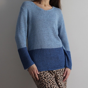 Può includere: Un maglione di lana blu e azzurro con scollo a V e maniche lunghe.