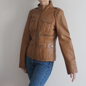 May include: A brown leather jacket with a zipper closure, multiple pockets, and a stand-up collar.