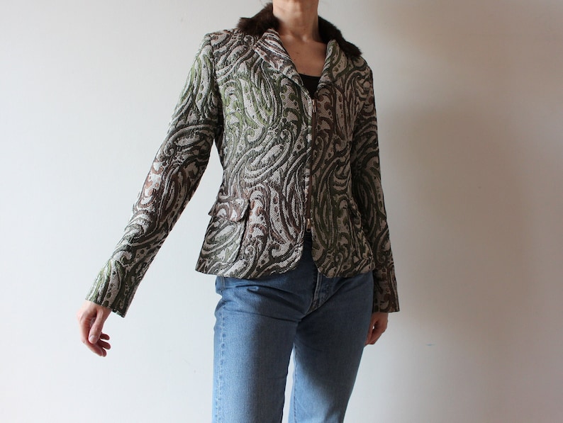 K&ouml;nnte beinhalten: Ein brauner, gr&uuml;ner und wei&szlig;er Blazer mit Paisley-Muster und einem Kunstfellkragen. Der Blazer hat einen Rei&szlig;verschluss und lange &Auml;rmel.
