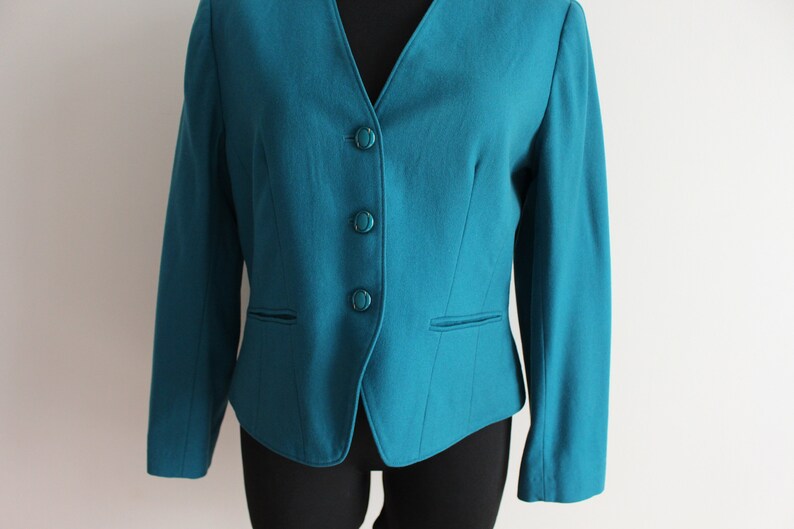 May include: A teal blue blazer with a v-neck and four buttons down the front.
