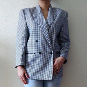 Könnte beinhalten: Ein schwarz-weiß kariertes Blazer mit doppelreihigem Verschluss und schwarzen Knöpfen. Der Blazer hat einen Schalkragen und lange Ärmel.