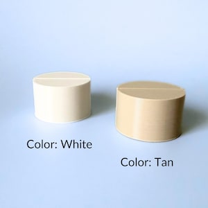 A white table number holder next to a tan table number holder. These holders are circular.