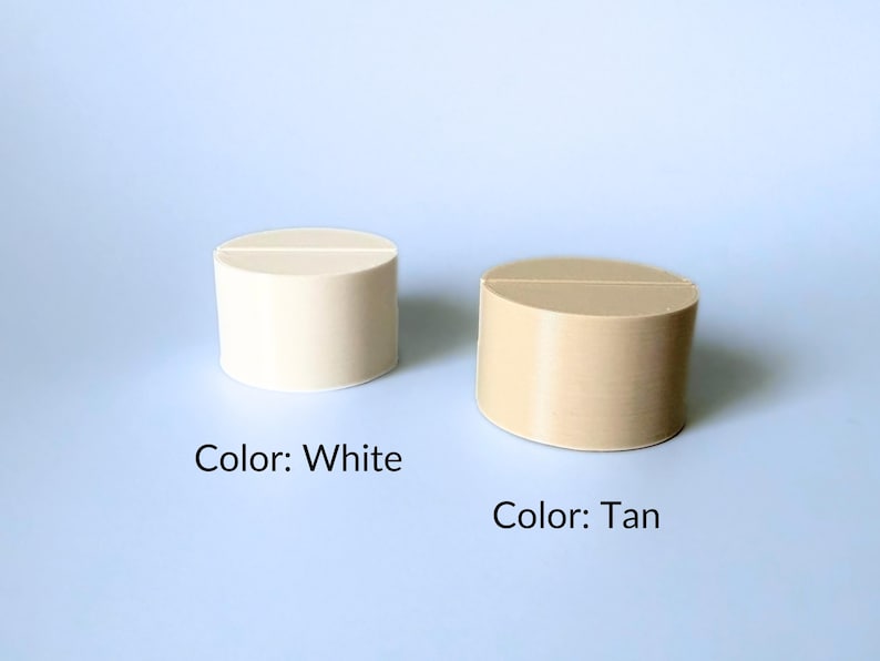 A white table number holder next to a tan table number holder. These holders are circular.