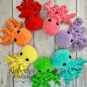 May include: A set of seven crocheted octopus plushies in various colours, including red, pink, orange, yellow, green, blue, and purple. Each octopus has eight tentacles and large, round eyes.