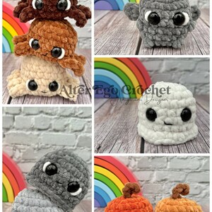 May include: A collection of crocheted plush toys in various colors and shapes, including a stack of three brown, orange, and white plush toys, a gray plush toy with a rainbow in the background, a white plush toy with a rainbow in the background, and two orange plush toys with brown stems.