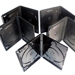 May include: A collection of black DVD cases, some open and some closed, arranged on a white surface. The cases are made of glossy plastic and have a circular hub in the center to hold a disc. The cases are empty.