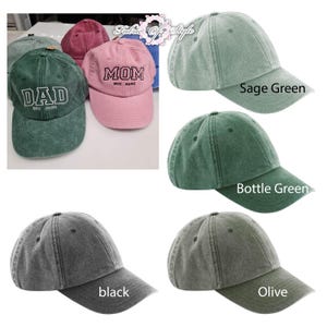 May include: A collection of baseball caps in various colors including sage green, bottle green, black, olive, pink, and maroon. Some caps feature embroidered text such as DAD EST. 2026 or MOM EST. 2026. The caps have a distressed, washed-out fabric finish.