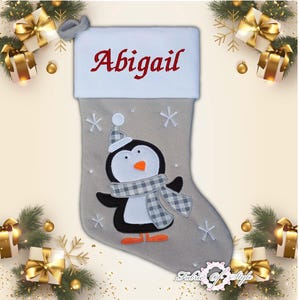 May include: A gray and white Christmas stocking with a penguin design and the name "Abigail" embroidered on the top.