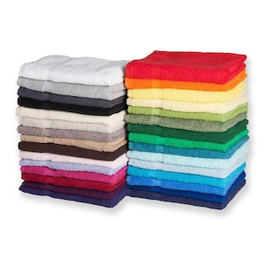 May include: Two stacks of folded rectangular cotton towels in a wide variety of colors. The left stack features neutral tones including white, gray, black, beige, and brown. The right stack displays vibrant colors like red, orange, yellow, green, blue, and purple.