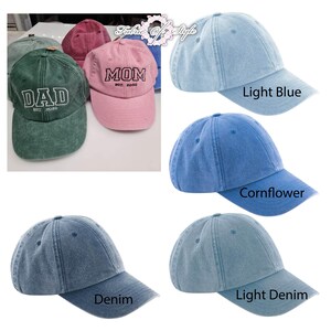 May include: A collection of baseball caps in various colors including green, pink, light blue, cornflower blue, denim, and light denim. Some caps feature embroidered text reading DAD EST. 2026 or MOM EST. 2026. The caps have a washed, textured finish.