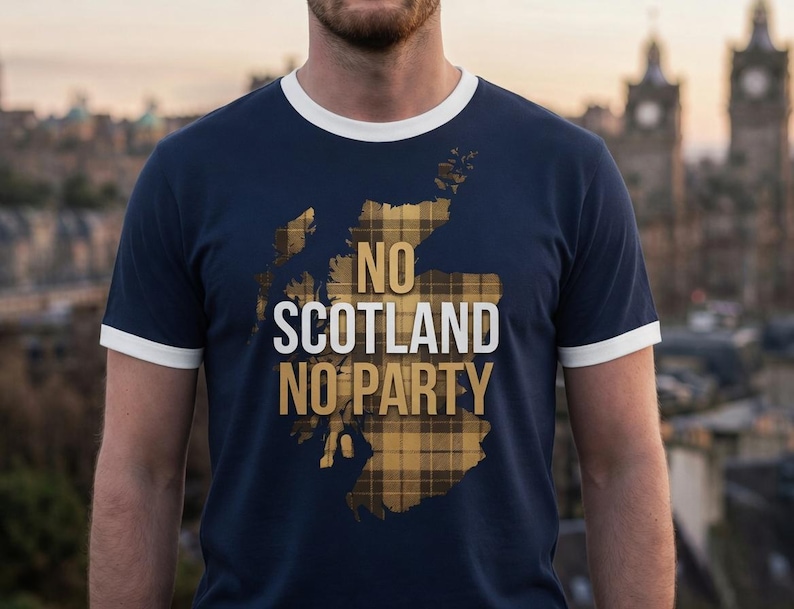 Może przedstawiać: Granatowa koszulka z białym wykończeniem, z mapą Szkocji w złotą kratę i napisem "NO SCOTLAND NO PARTY" w kolorze białym i złotym. Koszulka ma okrągły dekolt.