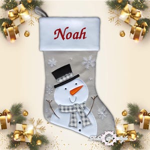 May include: A gray and white Christmas stocking with a snowman design. The stocking has a white cuff with the name "Noah" embroidered in red.