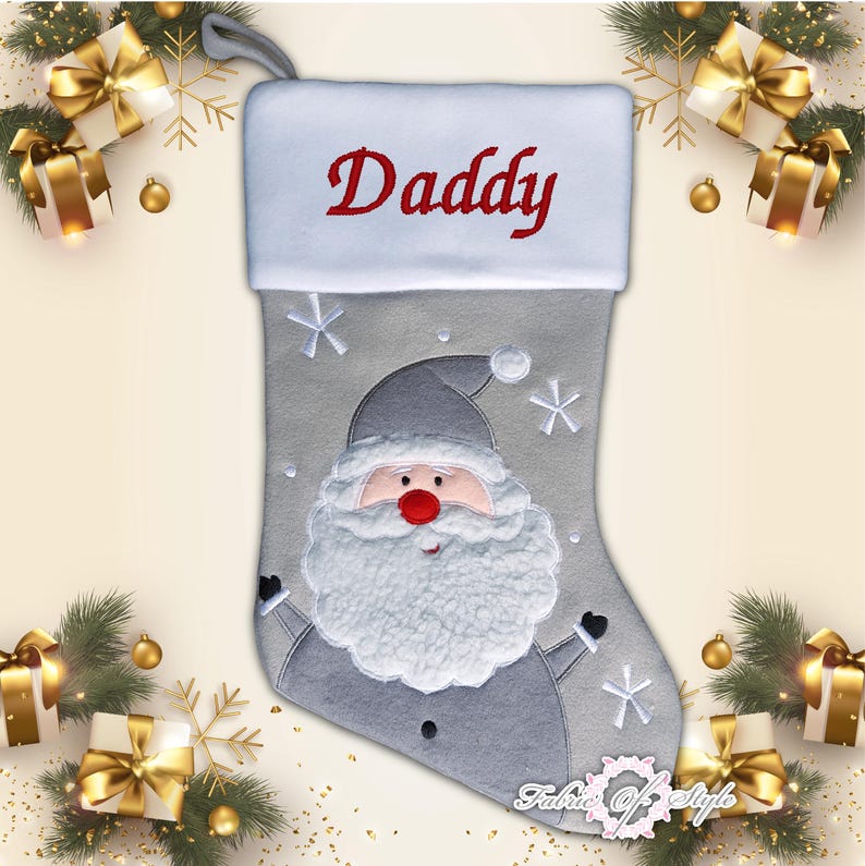 May include: Gray Christmas stocking with a white cuff and a Santa Claus design. The stocking has the word "Daddy" embroidered on the cuff in red thread.