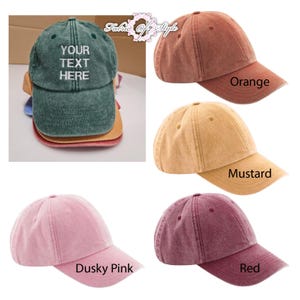 May include: A collection of six baseball caps in various colors including dark green, orange, mustard, dusky pink, and red. The dark green cap features the white embroidered text "YOUR TEXT HERE" on the front panel. Each cap has a curved brim.