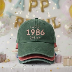 Op de afbeelding: Een stapel van drie baseballpetten in groen, rood en blauw. De bovenste pet is groen met de tekst "Limited 1986 Edition" in roze geborduurd. De achtergrond bevat ballonnen en een "Happy Birthday" banner.