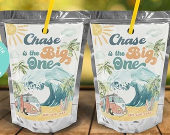 May include: Two clear plastic juice pouches with colorful labels. The labels feature a beach scene with a surfboard, palm trees, and a yellow van. The text on the labels reads "Chase is the Big One" and "First Birthday".