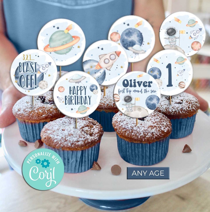 Pu&ograve; includere: Un set di 10 topper rotondi per cupcake a tema spaziale. I topper raffigurano pianeti, stelle, razzi e astronauti. Il testo sui topper include "3.2.1... Blast Off!", "Buon compleanno", "Oliver primo viaggio intorno al sole", e "1".