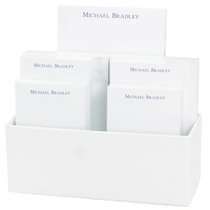 May include: A white desk organizer with four white notepads. Each notepad has the text "MICHAEL BRADLEY" printed in blue.
