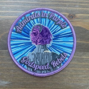 May include: Purple and blue embroidered patch with a woman in a purple dress and the text "Admirals in Purple, Godspeed Rebels".