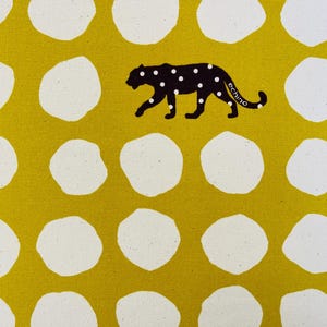 May include: Yellow fabric with white polka dots and a black silhouette of a leopard with the word "echino" printed on it. The fabric has the words "KOKKA CO LTD" printed on the side.