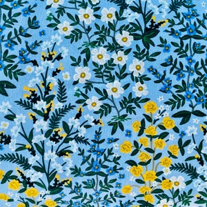 May include: A blue fabric with a floral pattern featuring white, yellow, and blue flowers. The fabric has a light blue background with a repeating pattern of flowers and leaves.