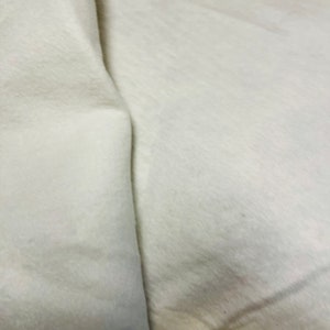 May include: A close-up of a white fabric surface with a fold in the middle.