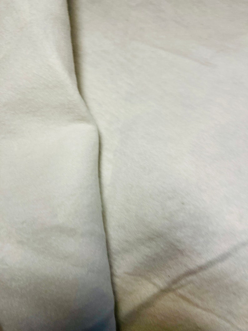 May include: A close-up of a white fabric surface with a fold in the middle.