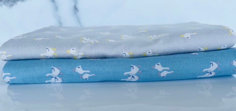 Puede incluir: Dos piezas de tela con un patr&oacute;n de p&aacute;jaros blancos. La tela superior es gris claro y la tela inferior es azul claro.