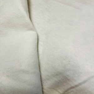 May include: A close-up of a white fabric surface with a fold in the middle.