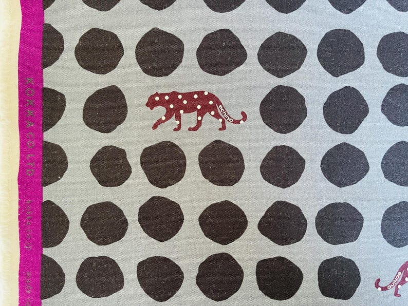 May include: A gray fabric with a repeating pattern of dark brown circles and a burgundy leopard print with the word "echino" printed on the leopard.