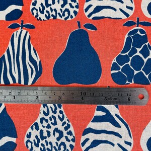May include: A coral orange fabric with a repeating pattern of blue and white pears. The pears have different patterns, including zebra stripes, leopard spots, and a giraffe-like pattern. A ruler is placed across the fabric, measuring 15 cm.
