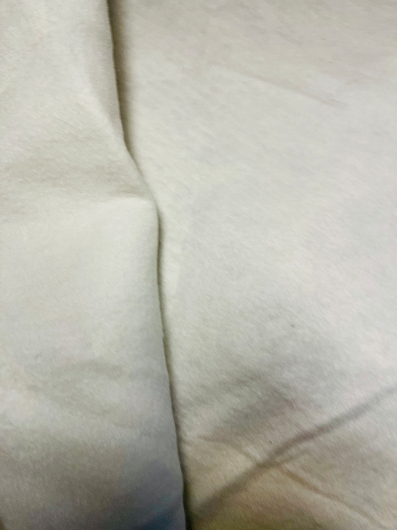 May include: A close-up of a white fabric surface with a fold in the middle.