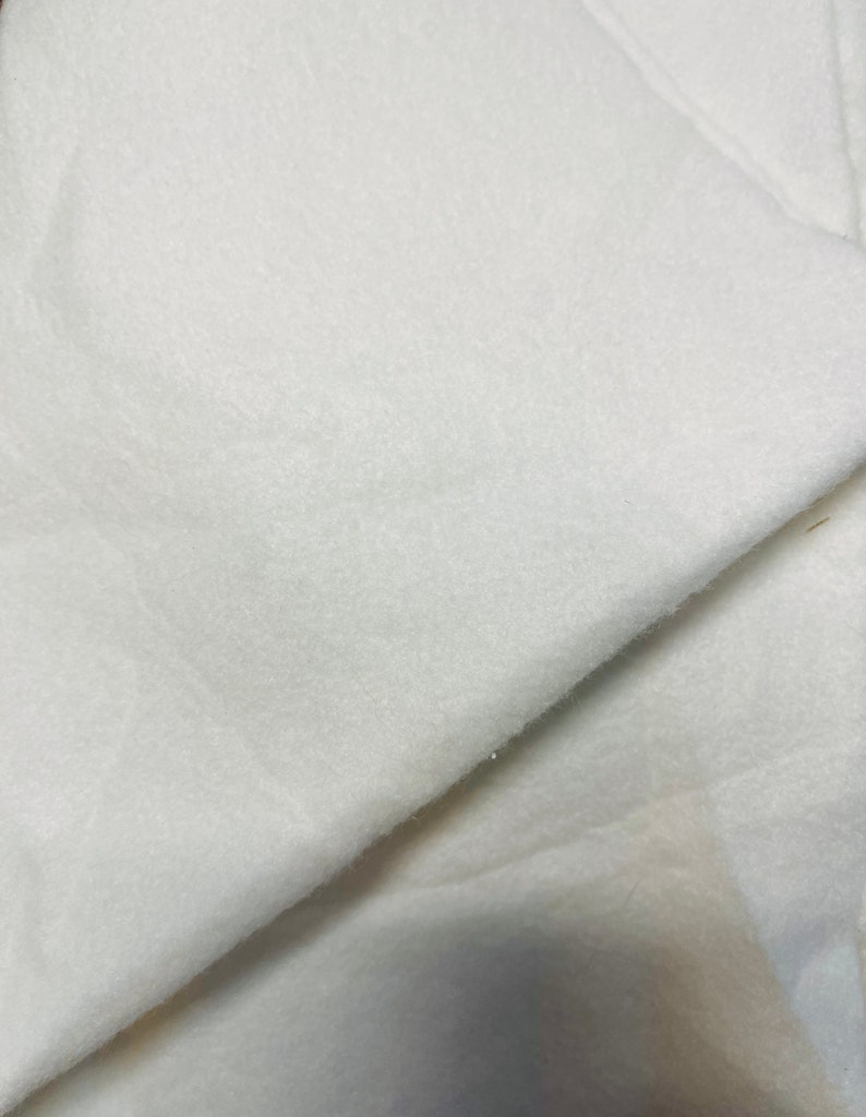 May include: White fleece fabric, soft and fluffy, with a smooth texture. The fabric is folded in half, showing the inside and outside of the material.