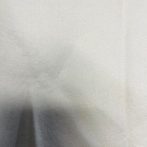 May include: A white, textured fabric surface.