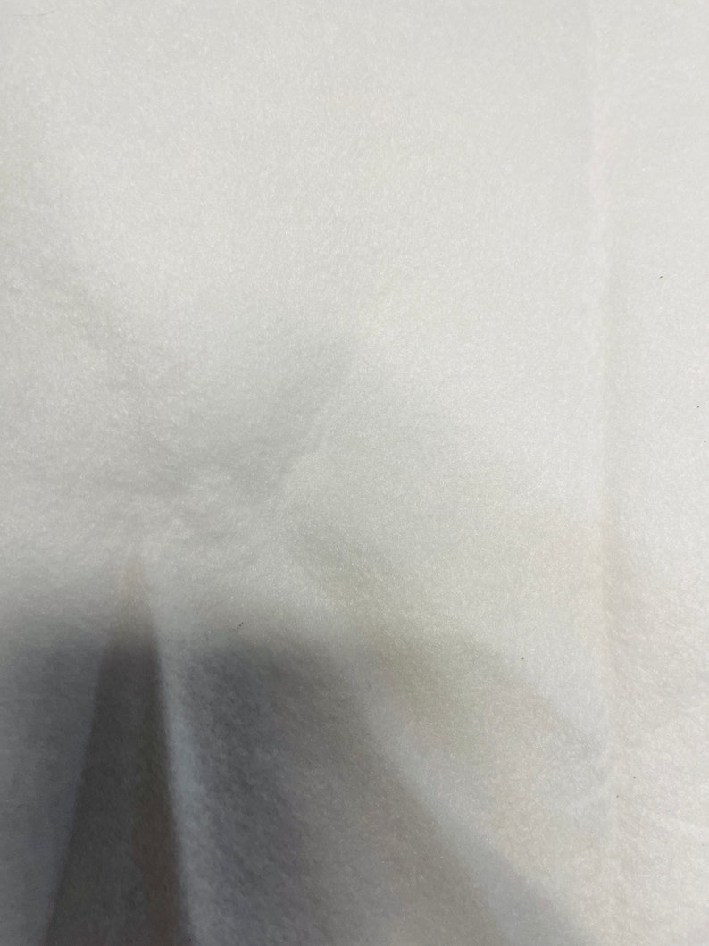 May include: A white, textured fabric surface.