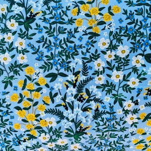 May include: A blue fabric with a floral pattern featuring white, yellow, and blue flowers. The fabric has a repeating pattern of small flowers and leaves.