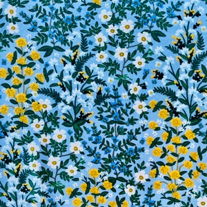 May include: A blue fabric with a floral pattern. The pattern features small white flowers, yellow flowers, and green leaves. The fabric has the text "SCREEN PRINTED IN JAPAN" on the left side.