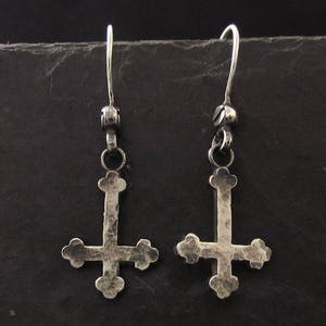 May include: A pair of silver earrings with a hammered upside-down cross design.